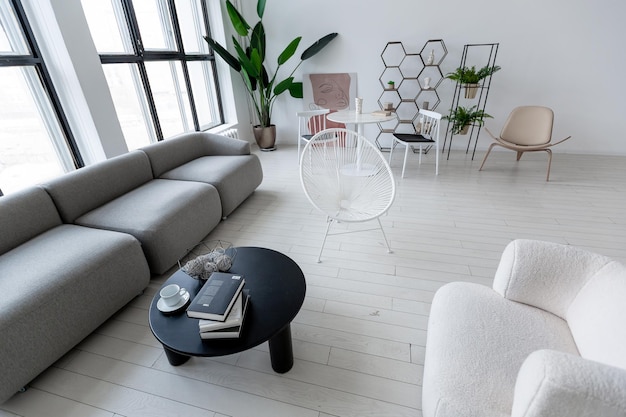 Il design moderno e minimalista degli interni di una camera monocromatica chiara e luminosa con mobili in bianco e nero, pareti bianche pulite e finestre enormi