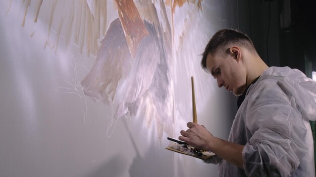 Il designer artista disegna un'aquila sul muro Il decoratore artigiano dipinge un'immagine con un colore ad olio acrilico guardando lo schizzo nel telefono