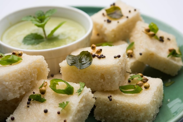 Il dhokla bianco khaman a base di riso o urad dal è una ricetta popolare per la colazione o gli snack del Gujarat, in India, servita con chutney verde e tè caldo. Messa a fuoco selettiva