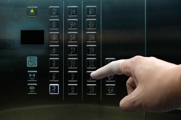 Il dito preme il pulsante dell'ascensore indossando un lettino per evitare il contatto diretto con germi e batteri.