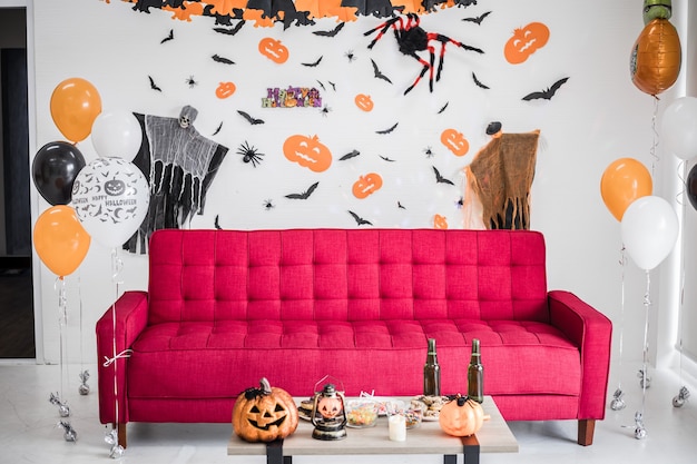 Il divano rosso nella stanza con la scena è ambientato ad Halloween. Ornamento da appendere, scene del festival di Halloween sul muro della stanza. Decorazione dell'arredamento di Halloween.