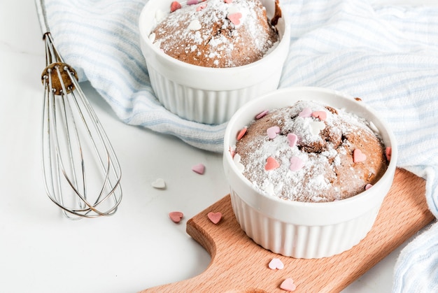 Il dolce o il brownie della tazza del cioccolato di San Valentino con zucchero in polvere e l'innamorato ha modellato spruzza, tavola bianca, vista superiore del copyspace