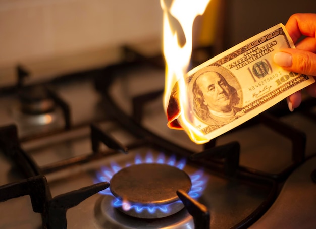 Il dollaro americano sta bruciando nel fuoco Bruciatore a gas sullo sfondo di cento dollari Il concetto l'aumento del prezzo del gas negli Stati Uniti Fornitura di gas costosa