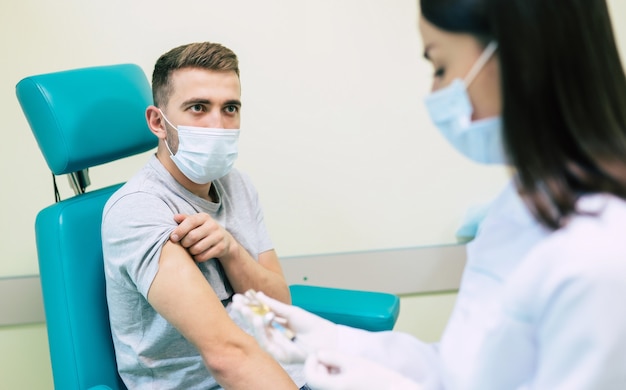 Il dottore con la maschera medica si sta preparando per il concetto di vaccinazione uomo, medicina e farmaco.