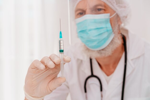 Il dottore con mascherina e siringa è pronto per somministrare il vaccino contro il covid 19