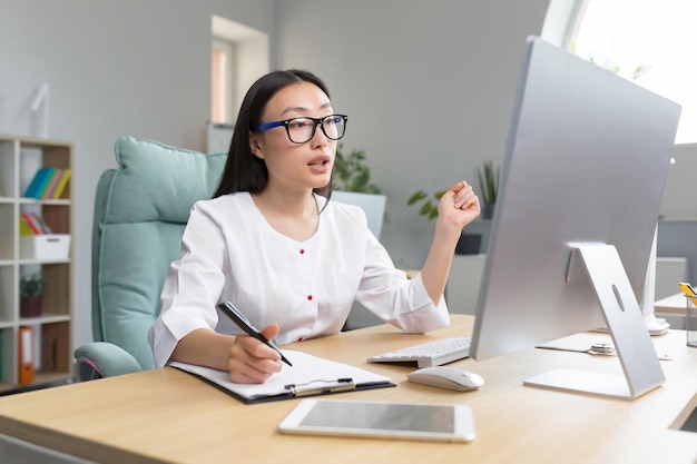 Il dottore è online, una giovane e bella dottoressa asiatica conduce una consulenza online come è