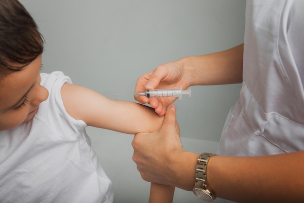 Il dottore vaccina il ragazzo nel braccio. Epidemia di coronavirus. concetto di vaccinazione. foto di alta qualità