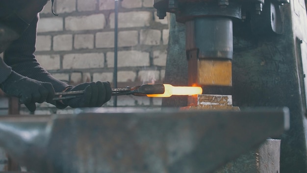 Il fabbro dell'uomo forgia il metallo al martello meccanico