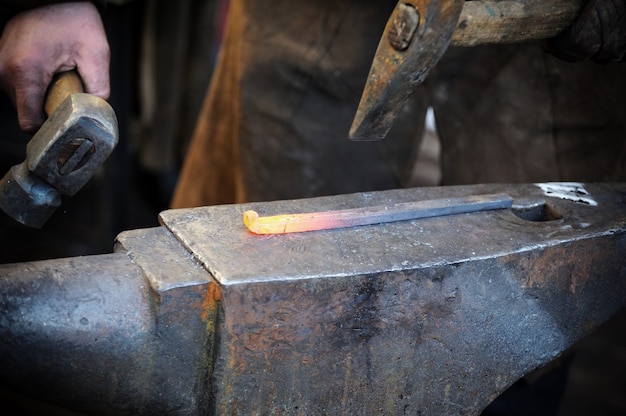 Il fabbro forgia un ferro di cavallo in una fucina