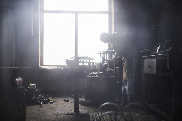 Il fabbro nella produzione di artigianato in metallo sull'incudine in officina