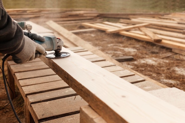 Il falegname sega la tavola di legno all'aperto primo piano utensile elettrico a mano Concetto di lavorazione del legno Tavole da segare