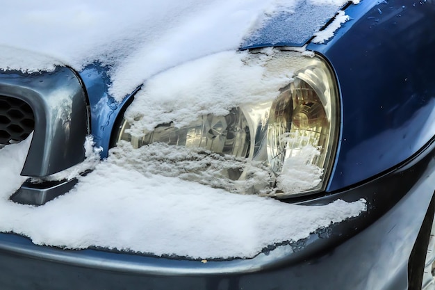 Il faro di un'auto è coperto di neve in primo piano