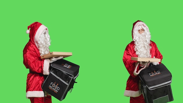 Il fattorino babbo natale nel personaggio che trasporta una borsa termica con fast food mentre celebra la vigilia di natale su schermo verde. Uomo vestito in costume festivo stagionale con abito rosso e bianco.