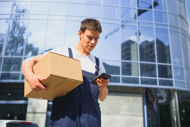 Il fattorino in uniforme tiene il pacco e il telefono