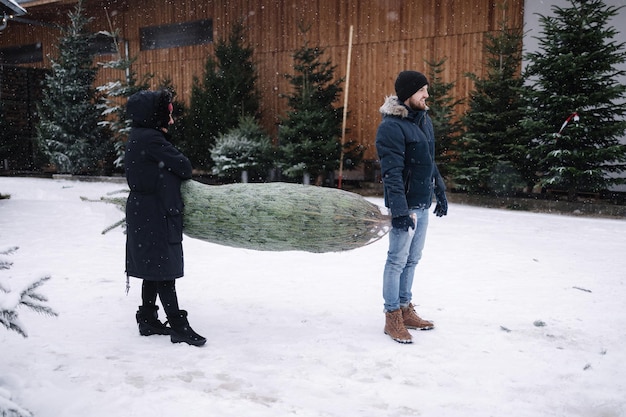 Il figlio con sua madre porta l'albero di natale in macchina conifera viva dal negozio ecologico nell'anticipazione del villaggio