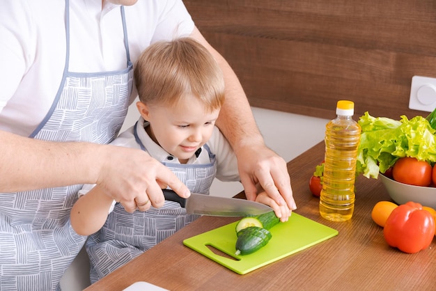 Il figlio del padre sta preparando le verdure fresche in cucina Taglio del bambino del papà e del ragazzo