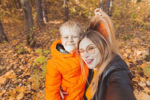 Il figlio e la madre si fanno selfie e si divertono nel tempo libero dei genitori single del parco autunnale e nella stagione autunnale