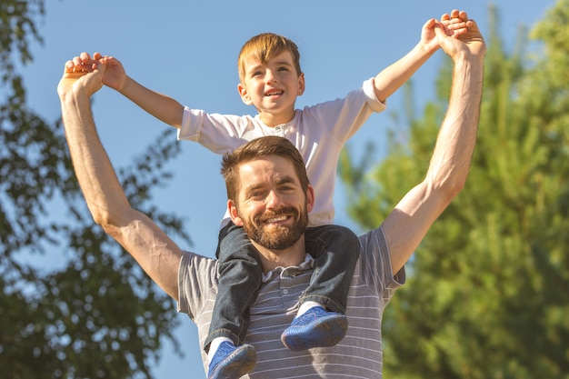 Il figlio felice si siede sul collo del padre