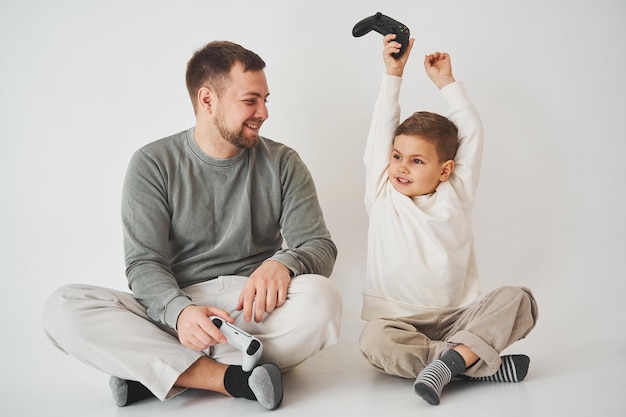 Il figlio ha vinto il padre nel gioco su console Il bambino felice con il gamepad alza le mani e si rallegra della vittoria nel gioco