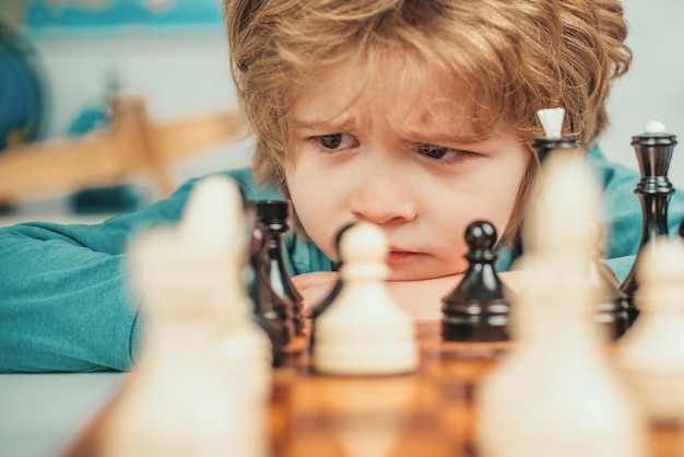 Il figlio sta giocando a scacchi e sorride a casa i bambini della scuola di scacchi un ragazzino intelligente che pensa agli scacchi