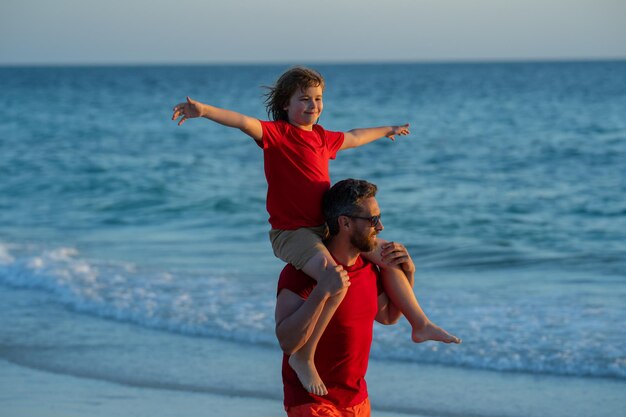 Il figlio sulle spalle del padre cavalca sulle spalle padre e figlio che camminano insieme sulla spiaggia paternità fami