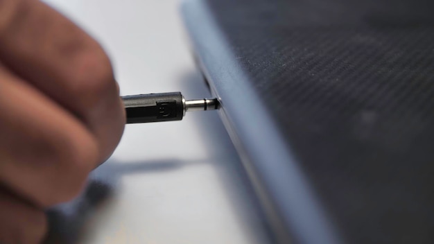 Il filo dell'auricolare inserito nel supporto del portatile close-up dell'uomo che inserisce il filo con il connettore per le cuffie