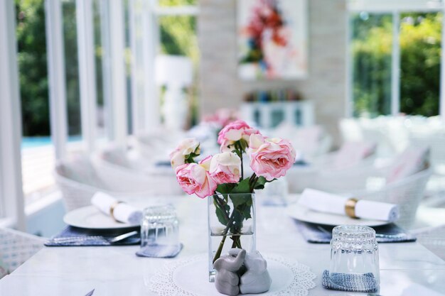 Il fiore di rose rosa naturale in vaso si trova sul tavolo in un caffè per lo sfondo