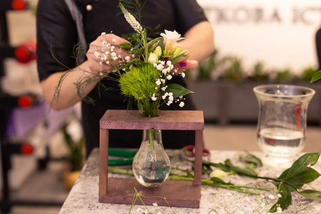 Il fiorista fa un mazzo. Composizione di fiori nella scatola di legno