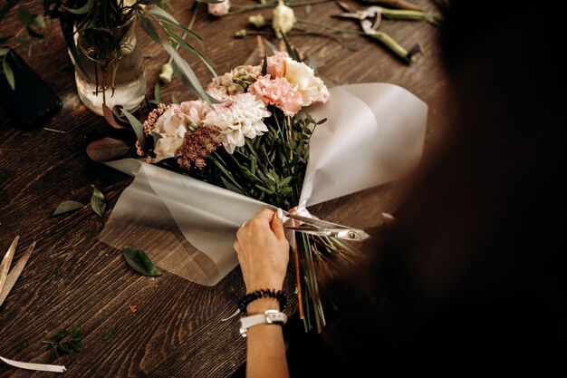 Il fiorista taglia un nastro sul bouquet di fiori freschi in colori pastello. .