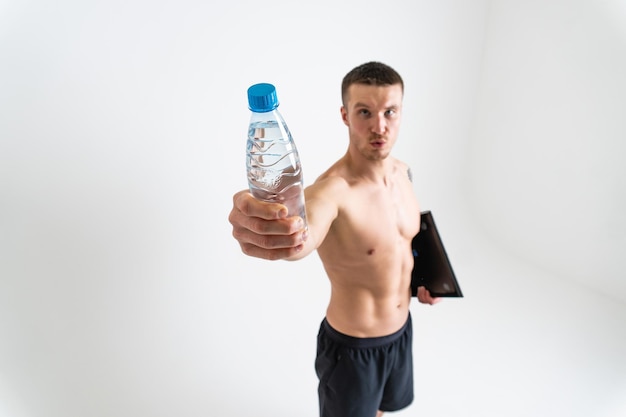 Il fitness maschile dell'acqua potabile viene pompato con un asciugamano su uno sfondo bianco isolato forte salute muscolare bevanda sana energia che tiene sfondo idratazione perfetta caucasico un muscolo