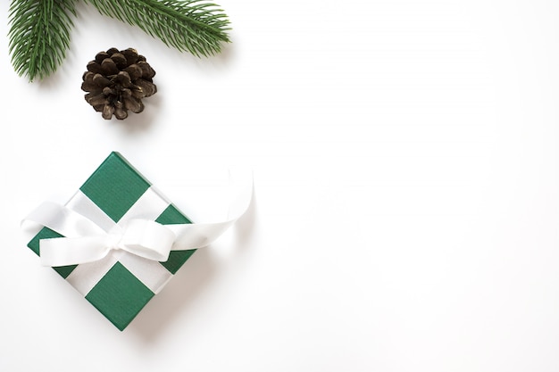 Il fondo di Natale con il contenitore di regalo verde sul piano bianco pone con lo spazio della copia.