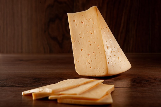 Il formaggio ordinario su un fondo di legno affettato con le fette giace sul tavolo