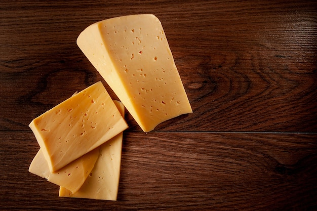 Il formaggio ordinario su un fondo di legno affettato con le fette giace sul tavolo