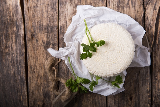 Il formaggio Suluguni viene tagliato a pezzi grossi su una tavola rotonda di legno. Guarnito con foglie di prezzemolo e pepe.