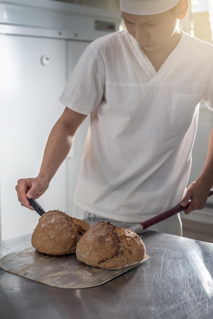 Il fornaio è un uomo nel processo di cottura del pane Produzione di prodotti da forno come piccola impresa