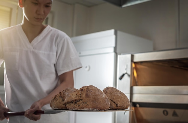 Il fornaio è un uomo nel processo di cottura del pane Produzione di prodotti da forno come piccola impresa