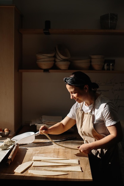 Il fornaio femminile arrotola l'impasto in rotoli il processo di cottura di un croissant Concetto di panetteria a fuoco selezionato