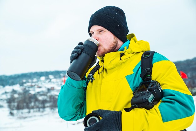 Il fotografo con la macchina fotografica che beve riscalda il tempo invernale del tè