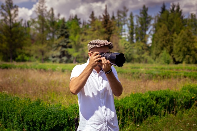 Il fotografo del giovane prende le immagini sulla macchina fotografica al parco verde