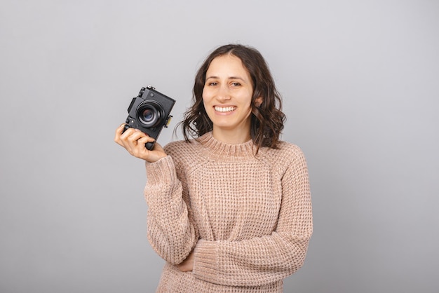 Il fotografo della donna tiene la macchina fotografica in una mano mentre sorride alla macchina fotografica