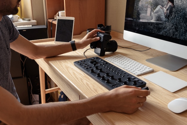 Il fotografo elabora le foto su un computer a un tavolo in una stanza