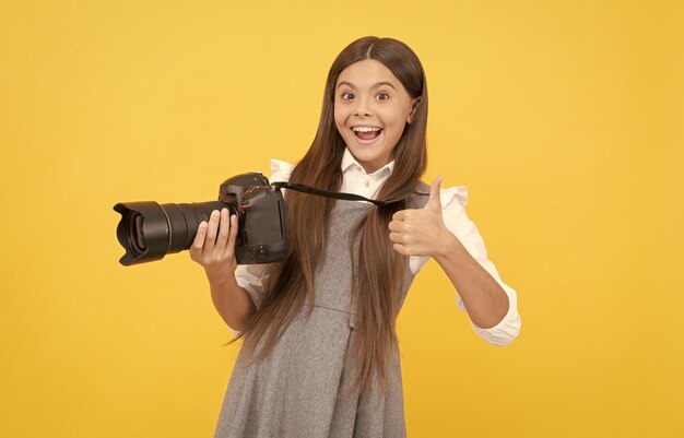 Il fotografo felice della ragazza teenager usa la fotocamera digitale per mostrare il pollice in su per fotografare