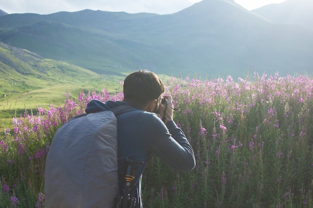 Il fotografo fotografa i fiori in montagna