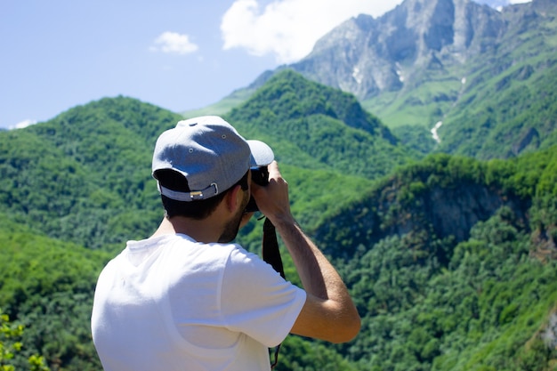 Il fotografo fotografa la montagna e la foresta sotto il cielo blu