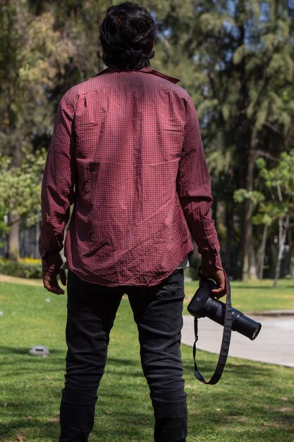 Il fotografo naturalista usa un teleobiettivo e tiene la fotocamera in mano mentre ammira gli alberi