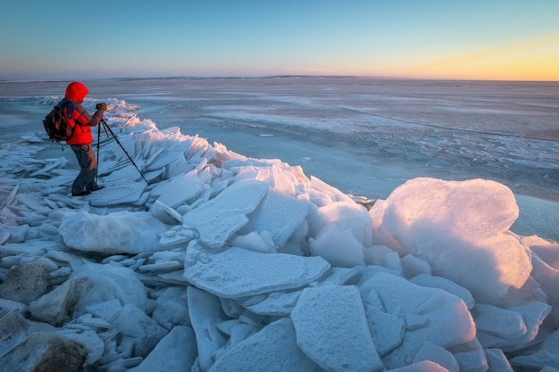 Il fotografo scatta una foto sulla costa del fiume in inverno