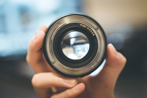 Il fotografo tiene in mano un obiettivo fotografico nel suo portatile sullo sfondo sfocato