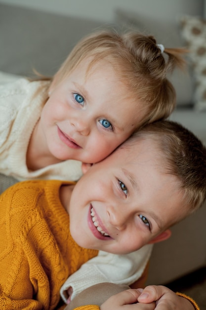 Il fratellino e la sorella in comodi maglioni lavorati a maglia giocano a casa. Ritratto di carino piccolo fratello e sorella. Autunno.