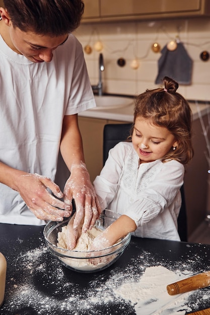 Il fratello con la sua sorellina prepara il cibo usando la farina in cucina e divertiti.