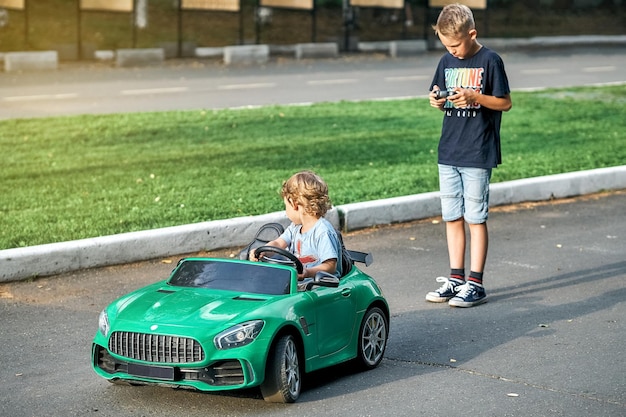 Il fratello maggiore controlla l'auto dei bambini con il telecomando a piedi con il fratellino nel parco pubblico